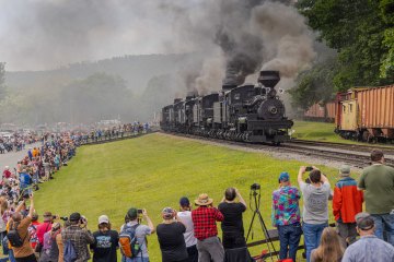 a group of people on a train track with smoke coming out of it